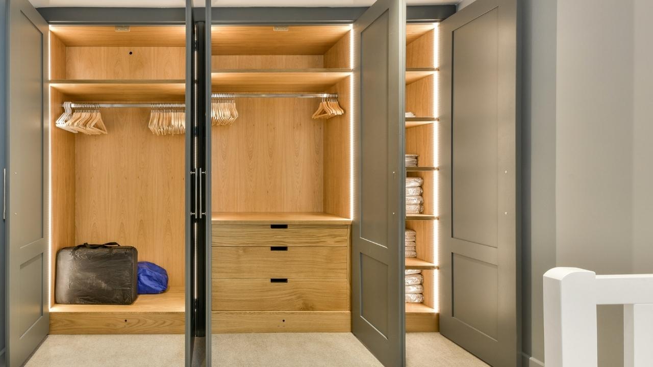 A walk-in closet with wooden shelves made by AS Fitted wardrobes and interiors